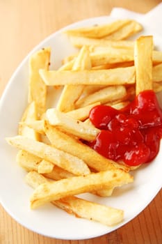 French fries with ketchup, sprinkled with kosher salt on a white dish