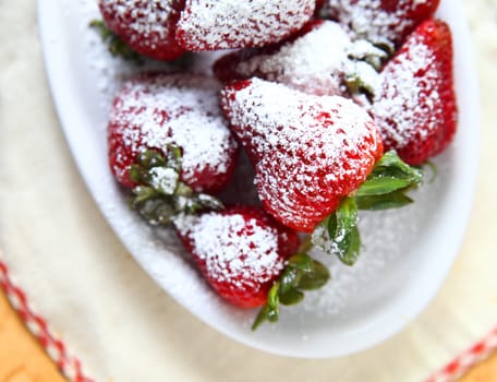 Fresh strawberries with powdered sugar in a white dish