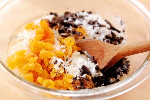 Mixing dried apricots into flour with chopped chocolate pieces