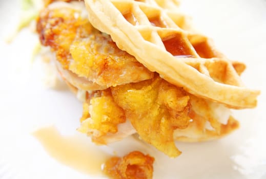 Fried chicken slices enclosed in a waffle with coleslaw and syrup