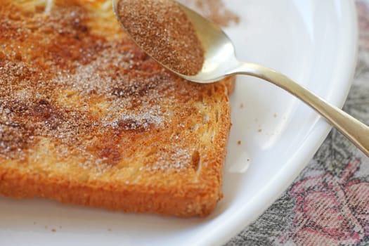 closeup of a slice of buttered toast with cinnamon sugar sprinkled over