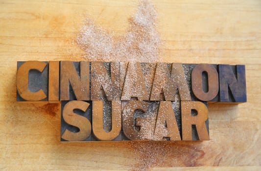 the words 'cinnamon sugar' in old wood type on a cutting board with cinnamon sugar sprinkled over