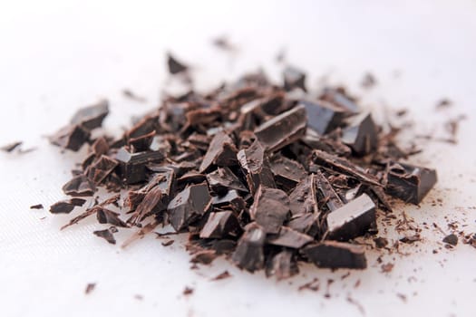 Dark chocolate pieces cut up on a white cutting board