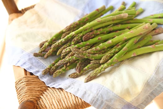 Fresh asparagus on a damaged old chair with a pastel cotton napkin