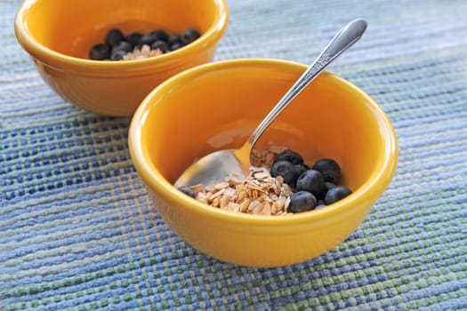 Uncooked oatmeal in yellow bowls with fresh blueberries and copy space