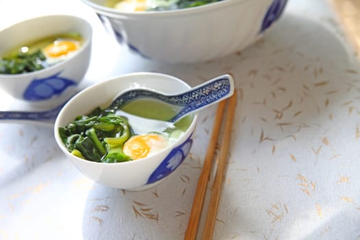 Large serving bowl with smaller bowls of spinach soup and poached eggs