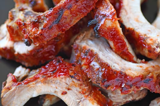 closeup view of oven-barbecued baby back ribs with a ketchup-based sauce