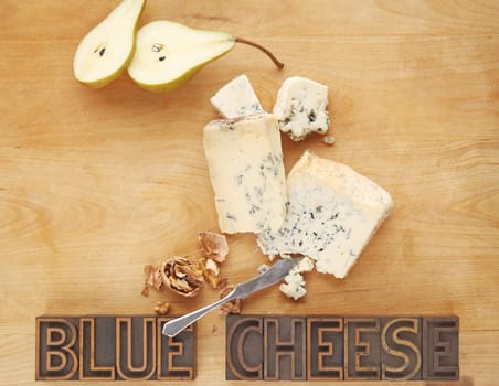 Blue cheese pieces with fresh pear, walnuts, and the words on a cutting board with copy space