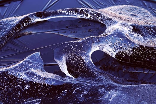 A chunk of ice with frozen air bubbles in the water. A small iceberg in the water