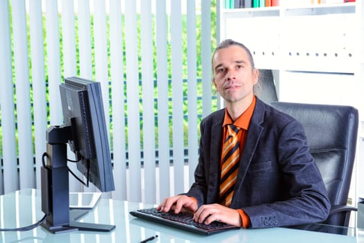 young business man at his desk looking in to the camera