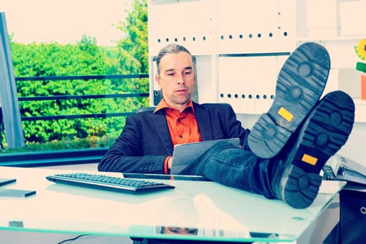 young business man at his desk relaxing with legs on desk