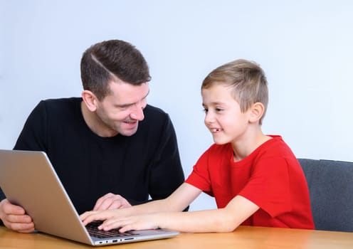 father and son using computer togetherat home