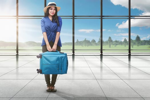 Young asian tourist woman with luggage standing on terminal airport