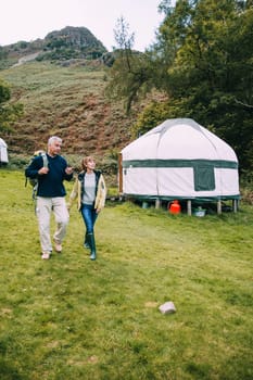Senior couple are leaving the yurt they have been camping in to go for a hike around the Lake District.