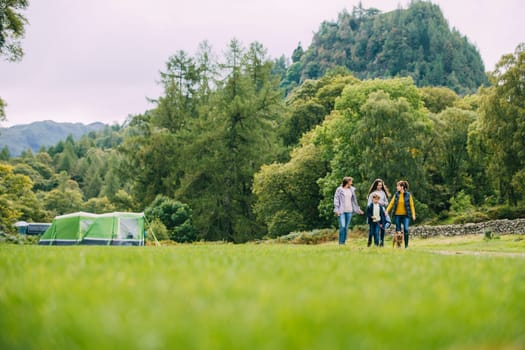 Three generation family have left their tent to go for a hike with their pet dog. There is a grandmother, a mother and her two children.