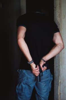 Athletic man, a dangerous gangster, reloads a gun behind his back
