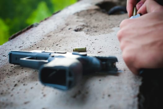 Man charges clip of pistol with bullets. Photo hands of paramilitary, reloading weapons. Preparation for shooting