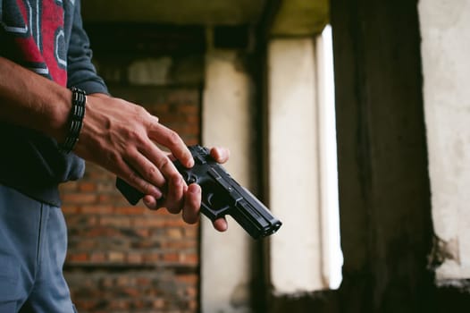 Dangerous athletic man holding a gun in his hand, close-up