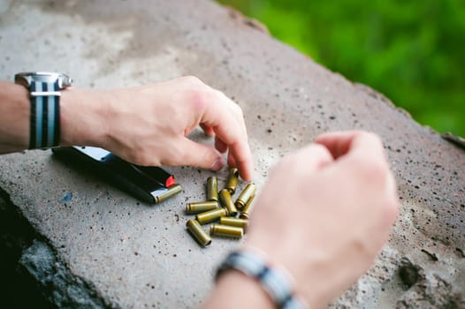 Man charges clip of pistol with bullets. Photo hands of paramilitary, reloading weapons. Preparation for shooting