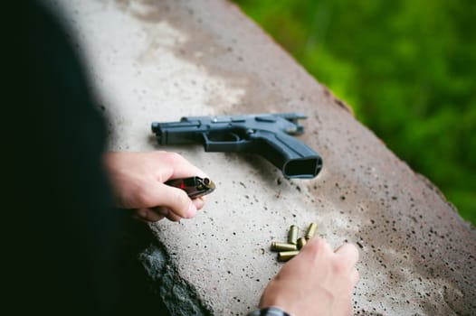 Man charges clip of pistol with bullets. Photo hands of paramilitary, reloading weapons. Preparation for shooting