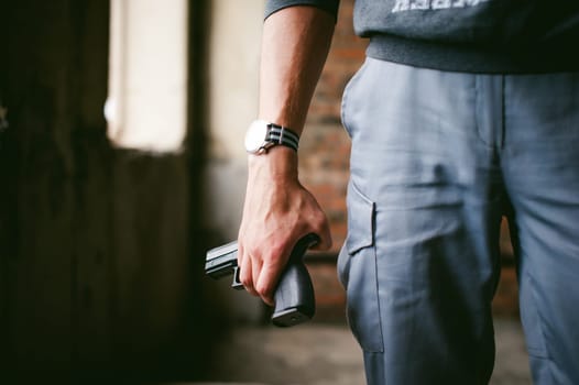 Dangerous athletic man, holds a gun in his hands, close-up. Wristband and watch
