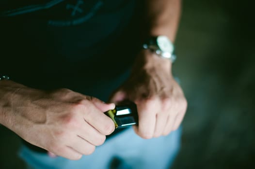Man charges clip of pistol with bullets. Photo hands of paramilitary, reloading weapons. Preparation for shooting