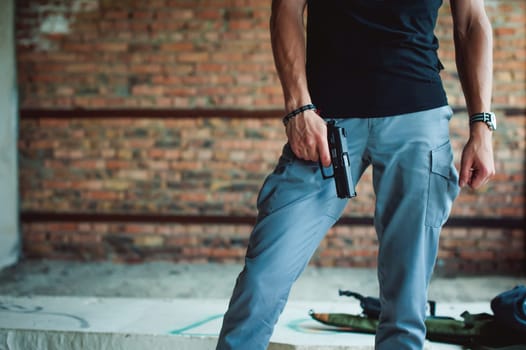 Dangerous athletic man holding a gun in his hand, close-up
