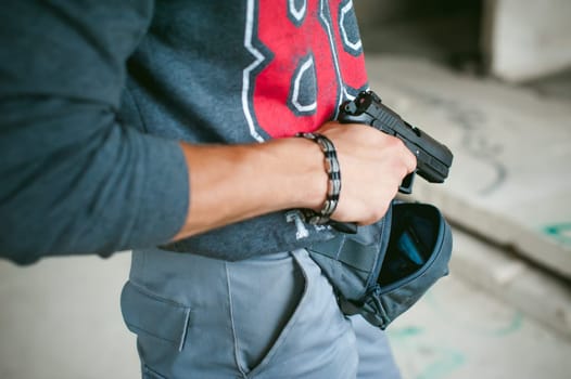 man pulls a gun out of his bag, holding it in his hand