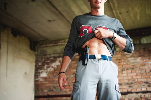 young athletic man holding a gun behind his belt.