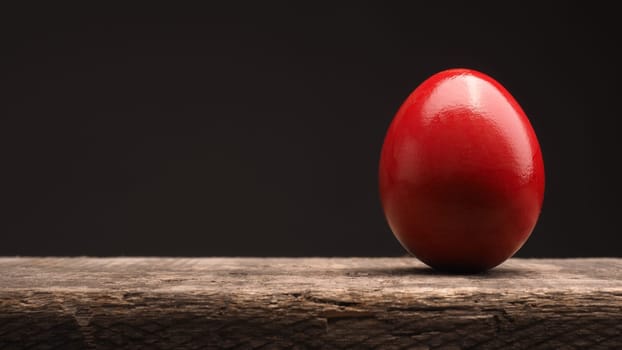 Red Easter egg on a rustic wooden table with space for text or image, Happy Easter background