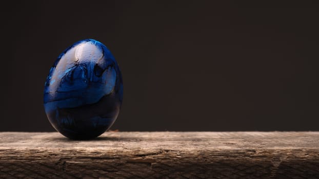 Blue Easter egg on a rustic wooden table with space for text or image, Happy Easter background