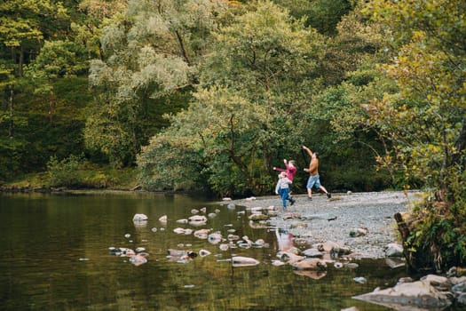 Two boys are skimming stones in a lake with their father.