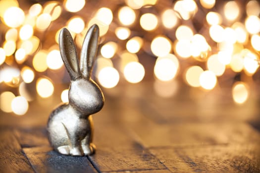 Little golden rabbit in front of fuzzy lights at Easter