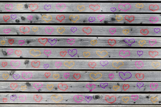 A wall of gray wood with many colorful hearts. Painted hearts on a gray wooden wall