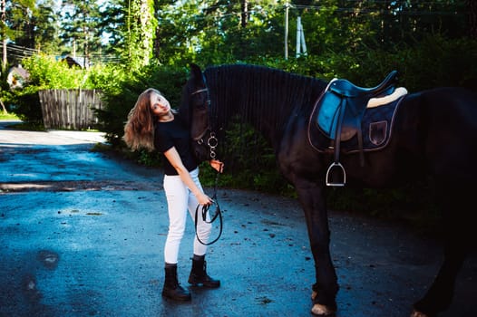Emotional  Portrait of a female in love with horses, black Friesian stallion thoroughbred pet, outdoors.