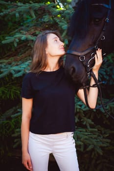 Emotional  Portrait of a female in love with horses, black Friesian stallion thoroughbred pet, outdoors.