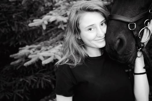 Emotional  Portrait of a female in love with horses, black Friesian stallion thoroughbred pet, outdoors.