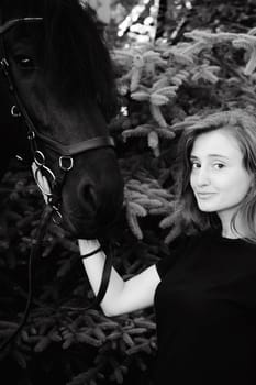 Emotional  Portrait of a female in love with horses, black Friesian stallion thoroughbred pet, outdoors.