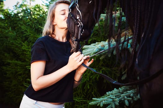 Emotional  Portrait of a female in love with horses, black Friesian stallion thoroughbred pet, outdoors.