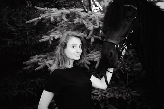 Emotional  Portrait of a female in love with horses, black Friesian stallion thoroughbred pet, outdoors.