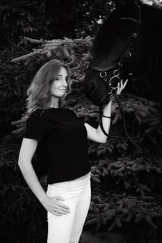 Emotional  Portrait of a female in love with horses, black Friesian stallion thoroughbred pet, outdoors.
