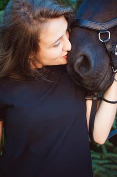 Emotional  Portrait of a female in love with horses, black Friesian stallion thoroughbred pet, outdoors.