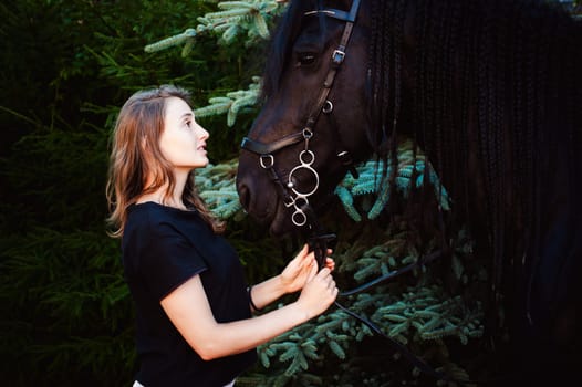 Emotional  Portrait of a female in love with horses, black Friesian stallion thoroughbred pet, outdoors.