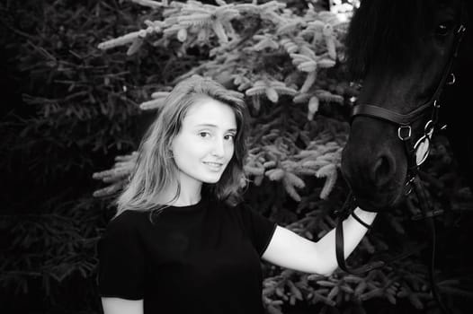 Emotional  Portrait of a female in love with horses, black Friesian stallion thoroughbred pet, outdoors.