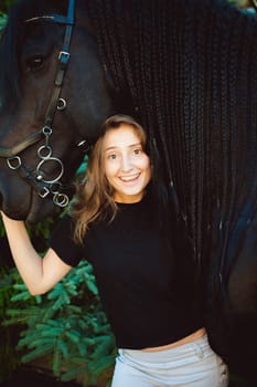 Emotional  Portrait of a female in love with horses, black Friesian stallion thoroughbred pet, outdoors.