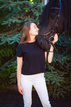 Emotional  Portrait of a female in love with horses, black Friesian stallion thoroughbred pet, outdoors.