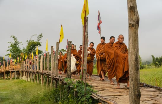 MAE HONG SON, THAILAND - NOVEMBER 21, 2015: Morning Buddhist Almsgiving at Zu Tong Pae bamboo bridge in Mae Hong Son, Thailand. Monks go on a daily almsround to collect food.