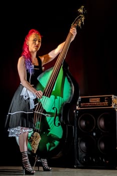 Rock'n'Roll singer with red hair and double bass against a dark background