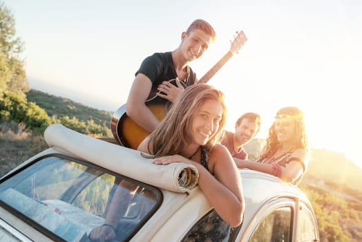 Group of happy people in a car at sunset in summer.