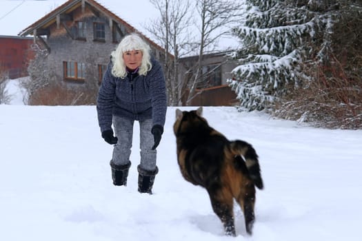 A woman plays with her cat in the snow. Funny cat photo of a jumping cat